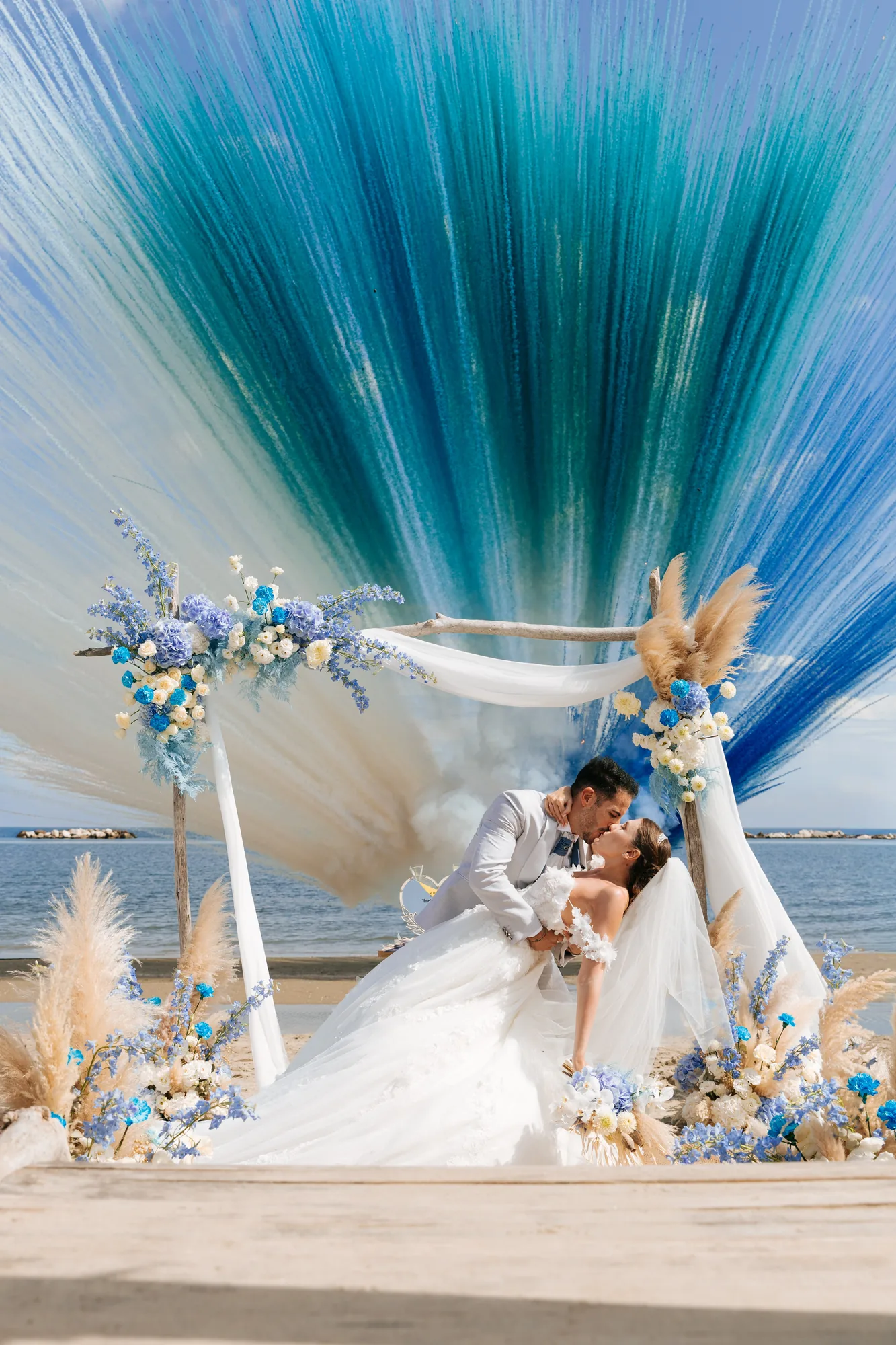Un bacio degli sposi tra fiori e drappi azzurri — Luméa Wedding