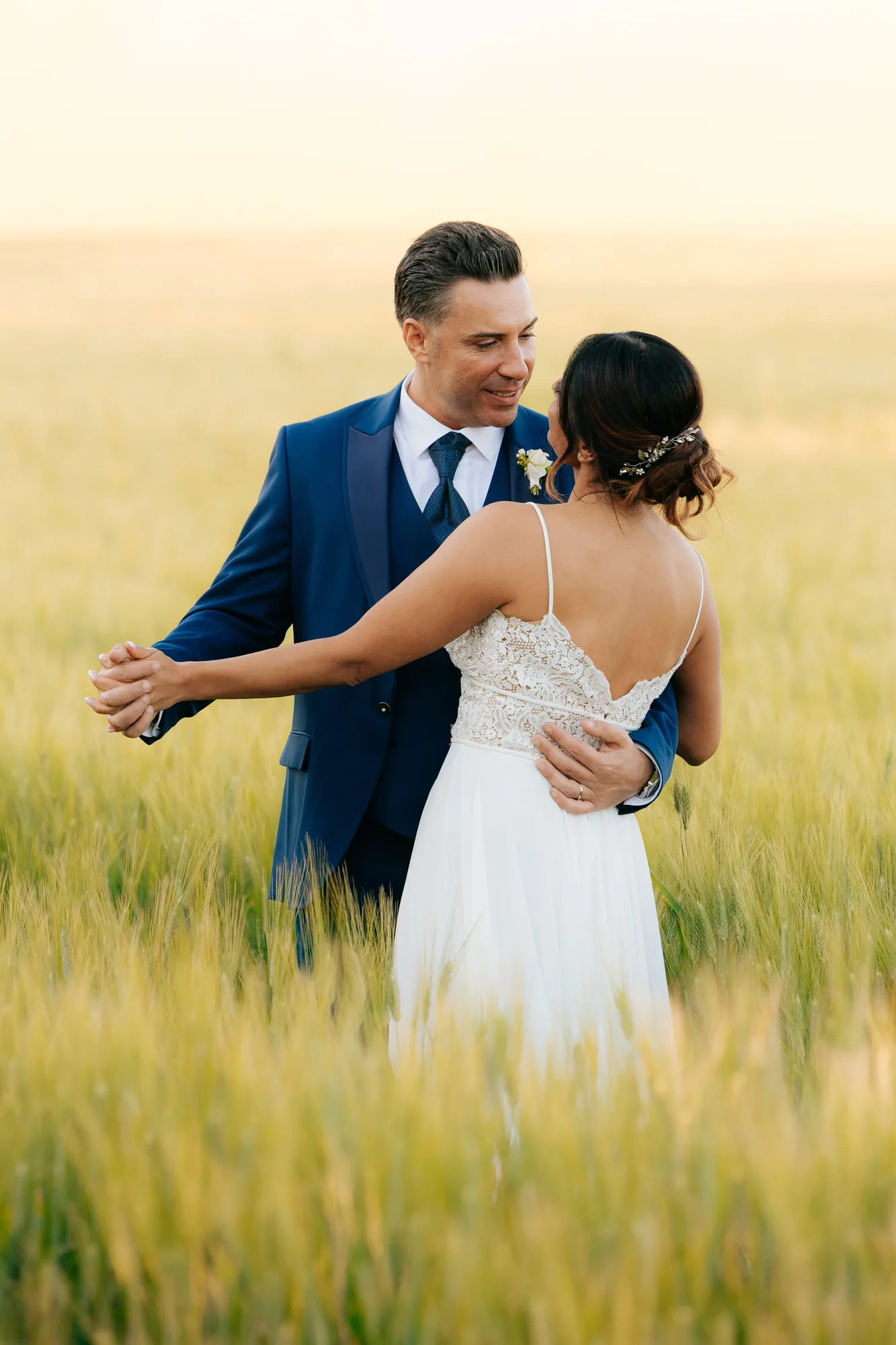 Gli sposi si abbracciano in un campo al tramonto — Luméa Wedding