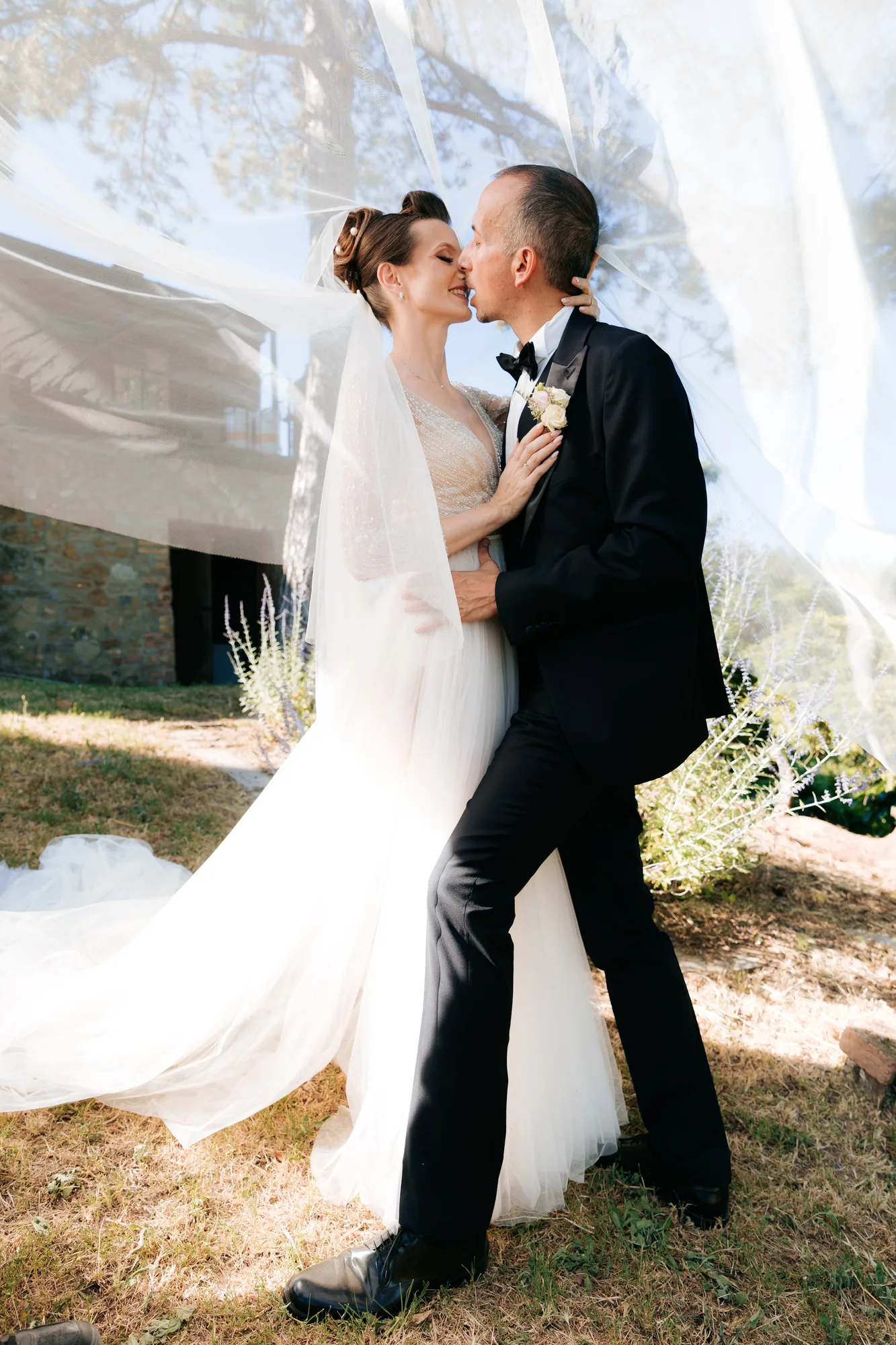 Gli sposi si baciano sotto il velo illuminato dal sole — Luméa Wedding
